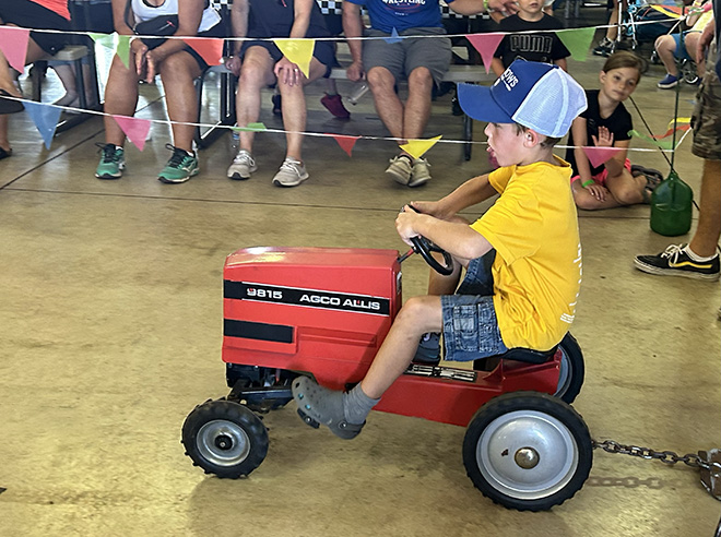 a boy pedaling on a minature tractor in the Kids' Pedal Tractor Pull at the Carver County Fair