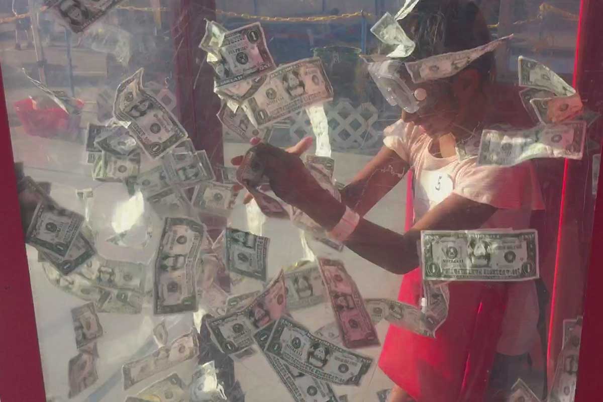 a kid in a money booth grabbing dollar bills