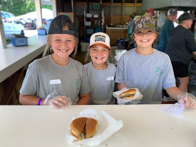 three kids serve burgers at the 4-H food stand