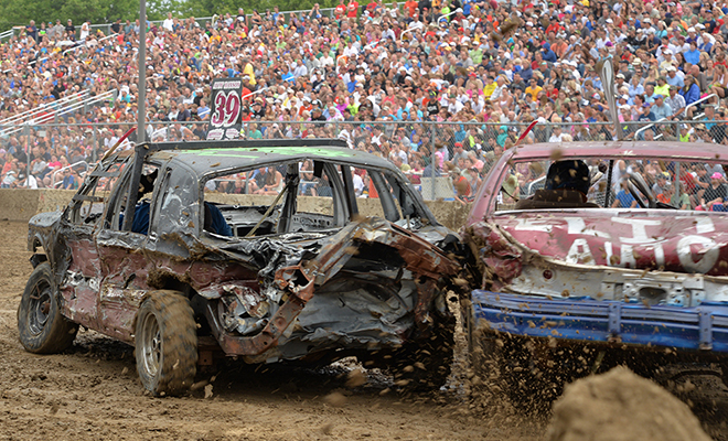 two smashed up cars kick up mud at the Carver County Fair Demolition Derby