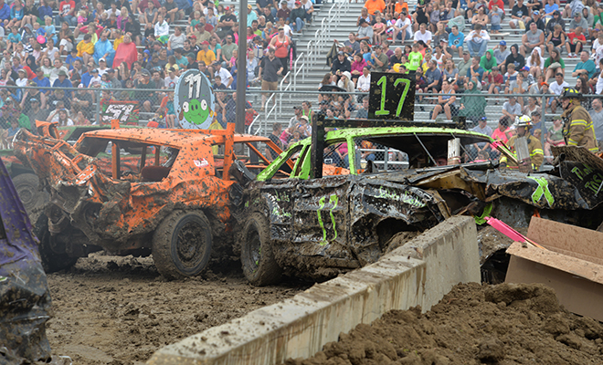 two smashed up cars kick up mud at the Carver County Fair Demolition Derby