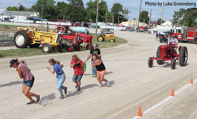 four women pulling a tractor using only a rope