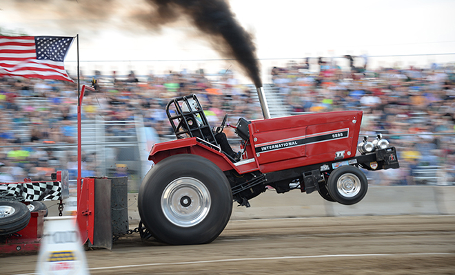 a red International tractor billows smoke as it pulls a sled at the Carver County Fair's NTPA Tractor Pull