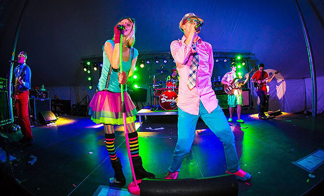 a man and a woman in neon clothing singing on stage